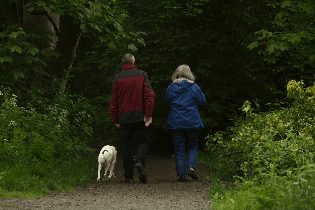 elderly couple on a walk in the woods with their dog-min